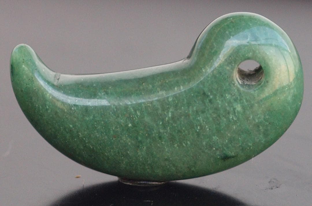 光にかざすと薄緑の細い帯状紋が出現、頭・胴の間には沈線、ずんぐり形の勾玉　沖縄の